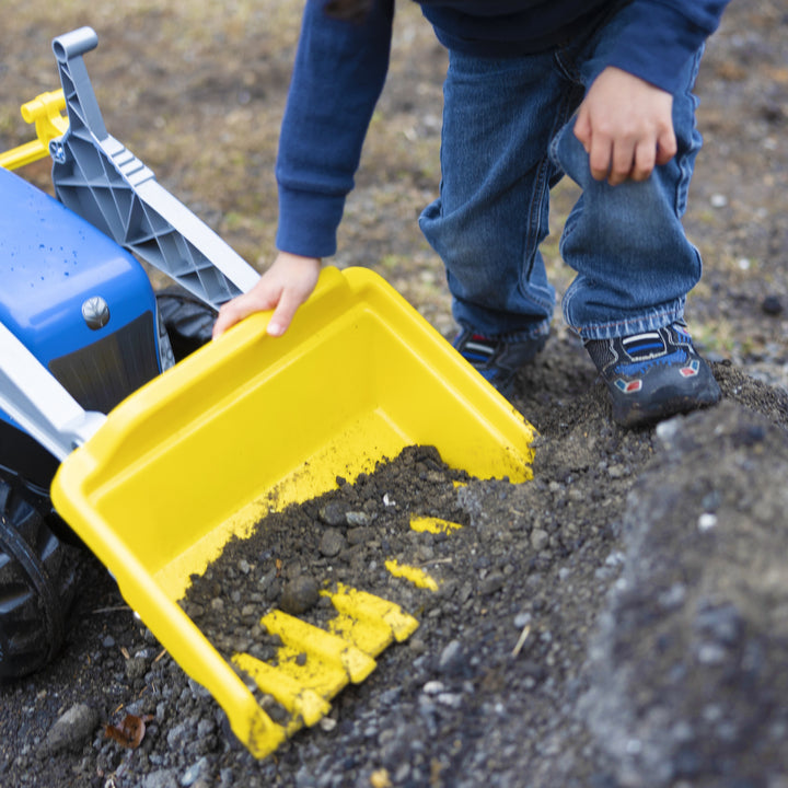Child playing with yellow front loader digging dirt on the New Holland Front Load Kid Tractor w/Trailer