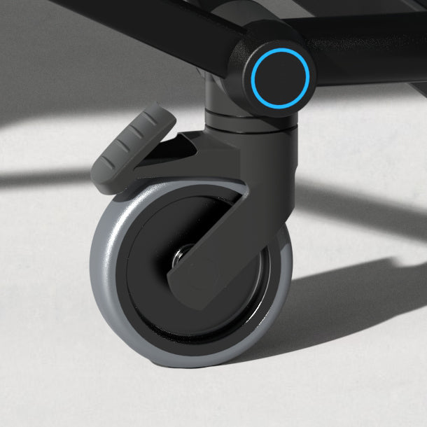 Close-up of a black and gray caster wheel with a foot-operated brake on a smooth light floor surface