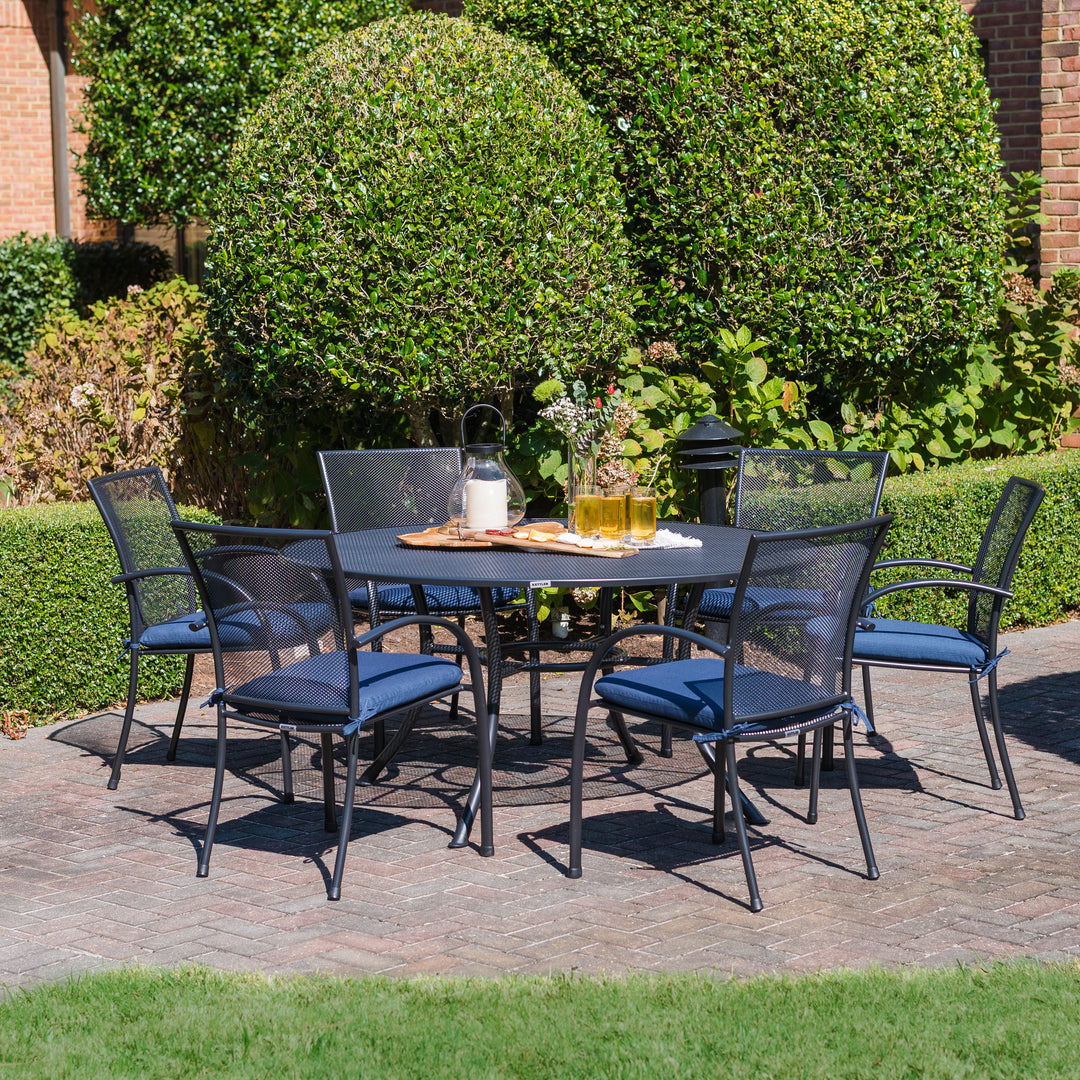 Pilano Wrought Iron Stackable Arm Chair set of 6 with iron grey armchairs around a round patio table outdoors.