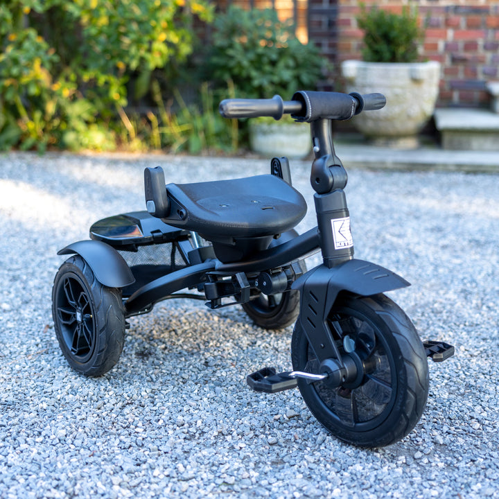 KETTLER Air Navigator 6-in-1 Tricycle in black with adjustable seat and pedals on gravel surface outdoors.