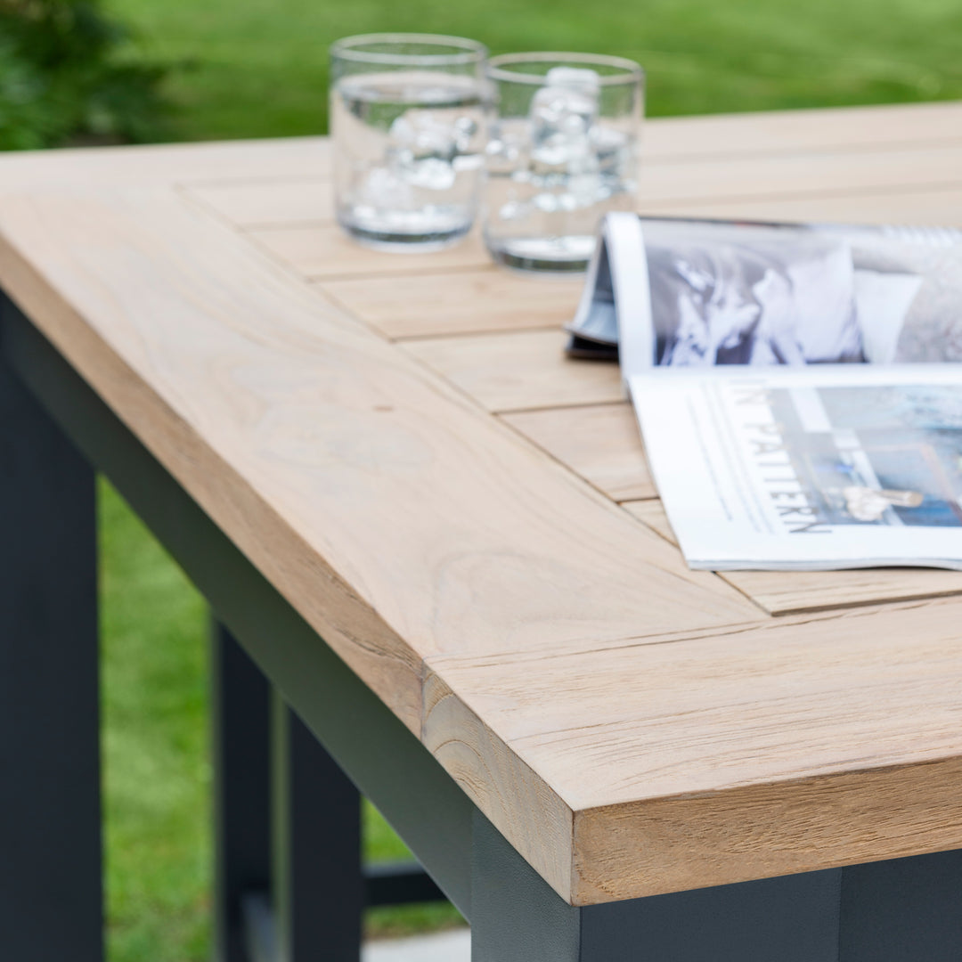 40-inch Elba Dining Table With Teak Top featuring a solid teak surface and rustproof charcoal aluminum frame outdoors.