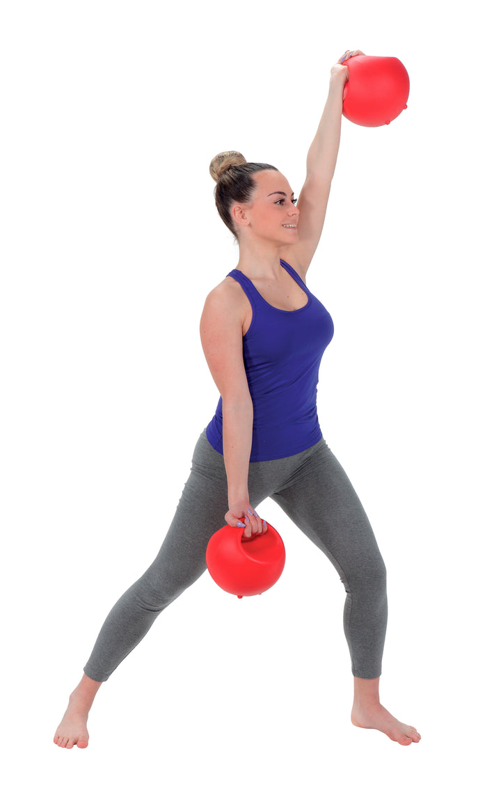 Woman exercising with red Gymnic Training Bowl Set for strength and endurance workout, holding one overhead and one down.