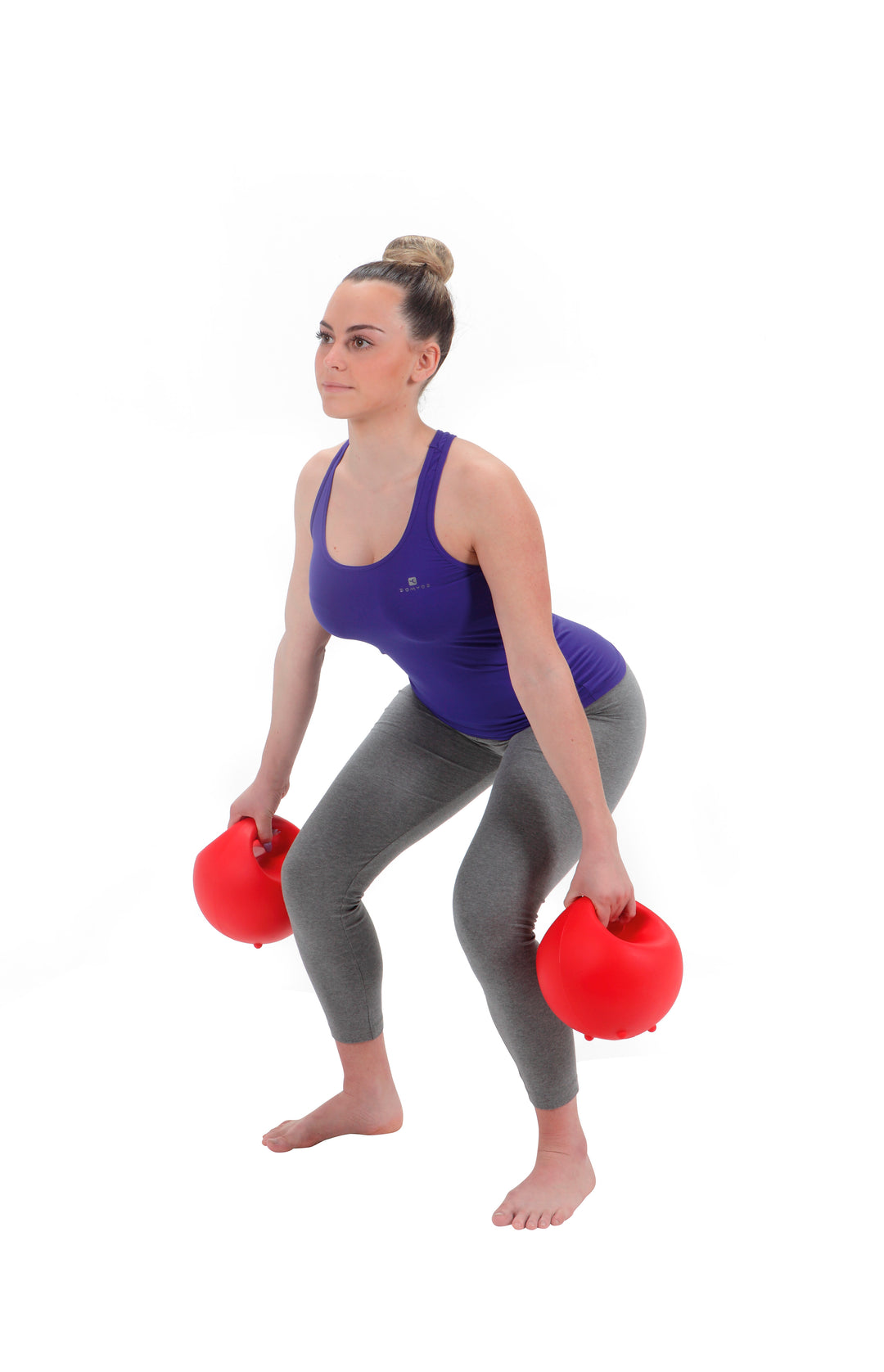 Woman performing squat exercise holding red Gymnic Training Bowl Set filled weights with handles for grip.