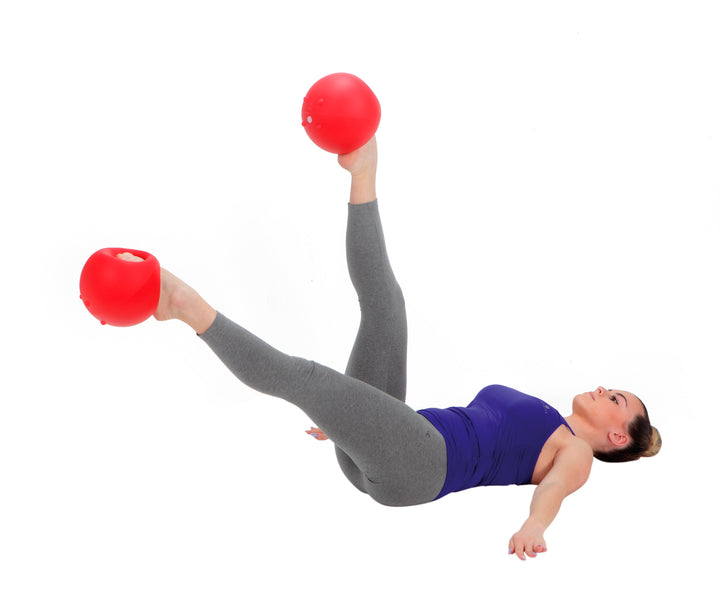 Woman exercising on floor using Gymnic Training Bowl Set held by hands and feet for strength training
