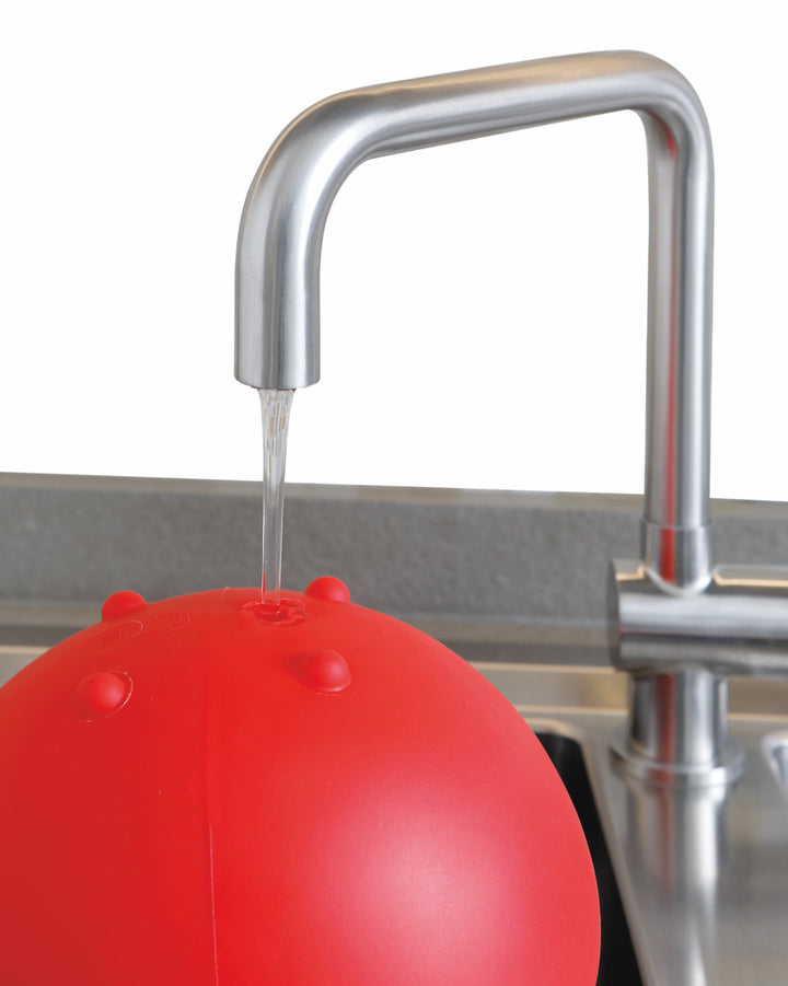 Gymnic Training Bowl Set being filled with water from a kitchen faucet, ready for adjustable weight exercise use.