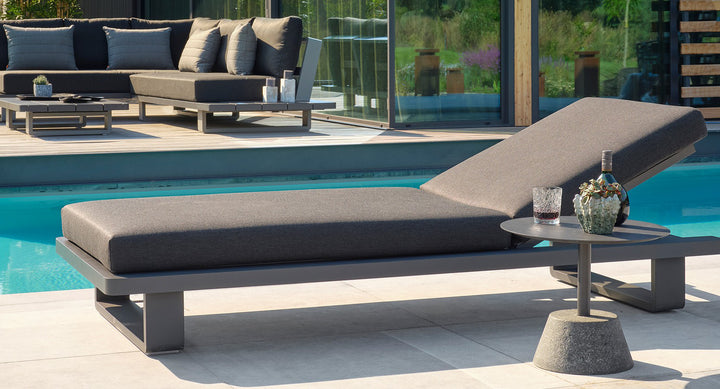 Fitz Roy Aluminum Lounger with charcoal cushions beside pool, featuring adjustable back and sleek lava aluminum frame.