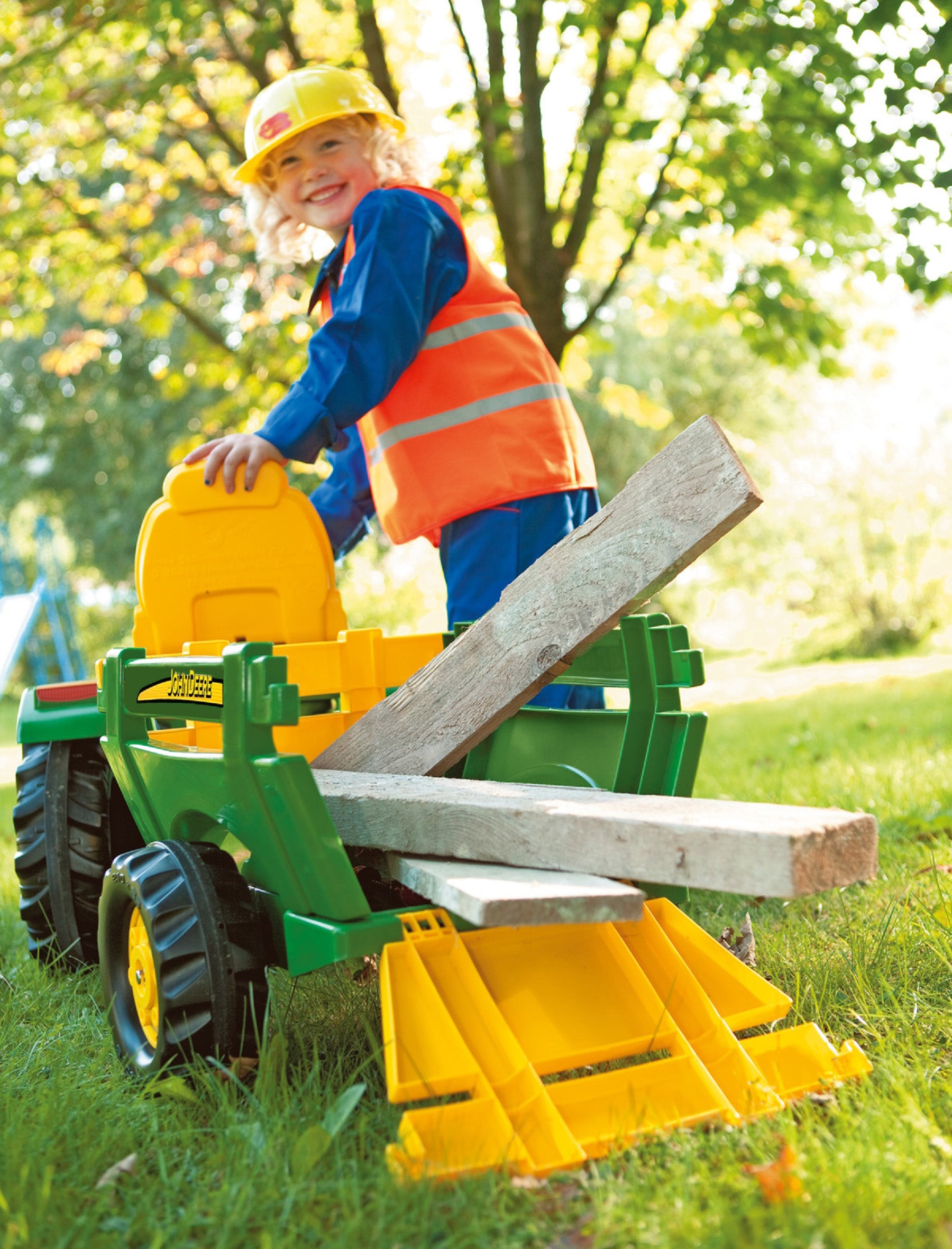 Lifelstyle image of child using john deere tractor trailer to load and transport wood