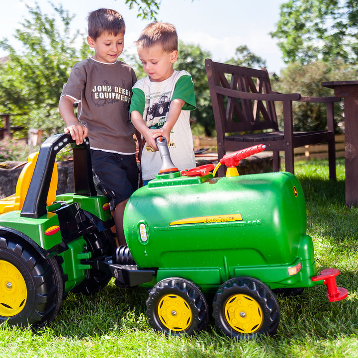 John Deere Water Tanker With Pump & Spray Gun hitched to pedal tractor with two boys playing outdoors.