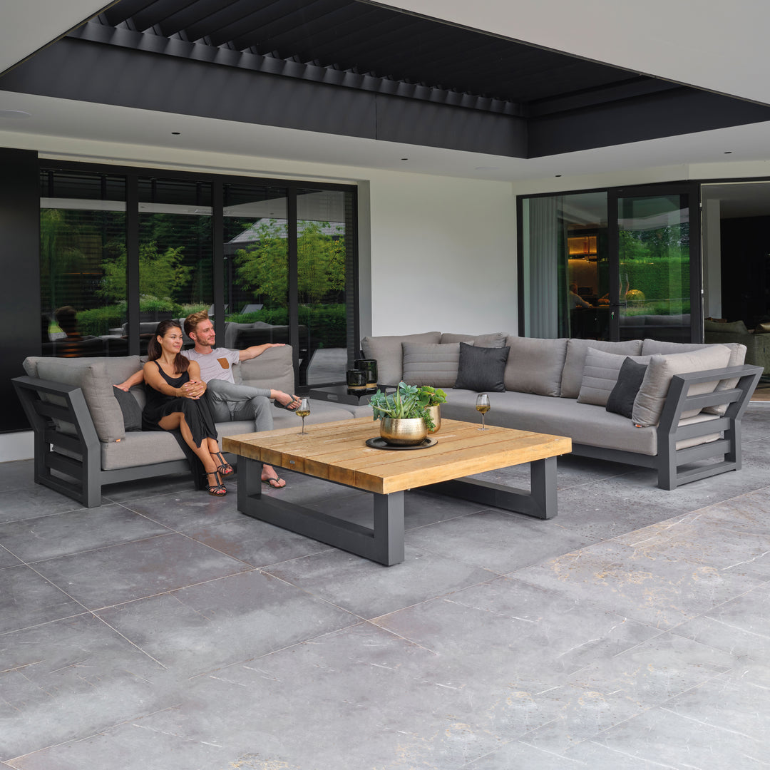 Nevada Large Corner Conversation Set with lava aluminum frame, teak table, and canvas soot cushions on outdoor patio.