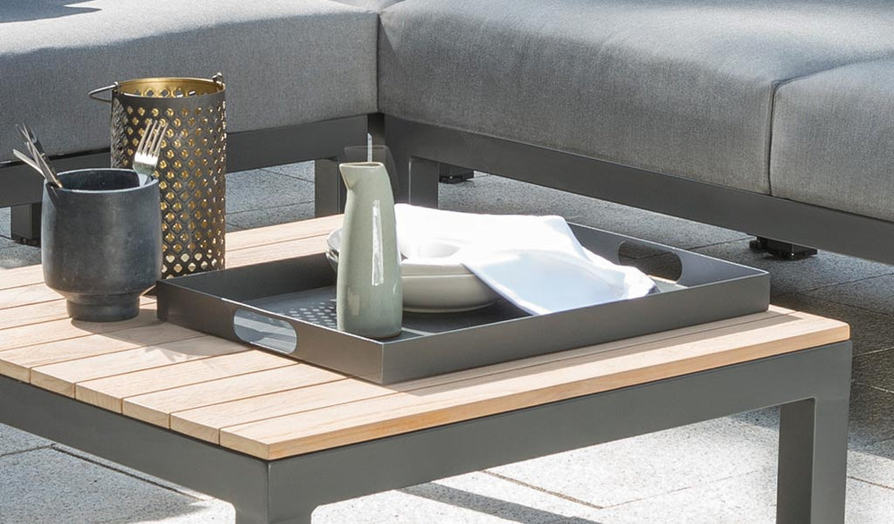 Elba Powder Coated Aluminum Serving Tray in charcoal with integrated handles on a patio table holding dishes and a pitcher.