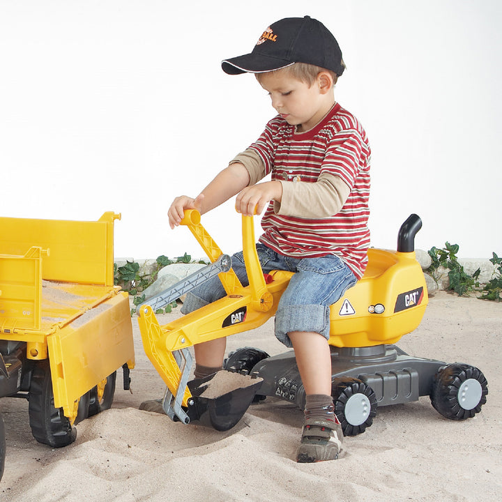 Child playing with the CAT Ride-On Digger, a yellow excavator toy with working levers and 360-degree rotation.