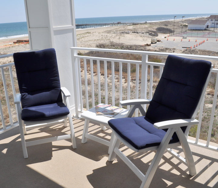 Multi Position Hinged Chair Cushions in navy blue on white outdoor chairs on balcony by the beach.