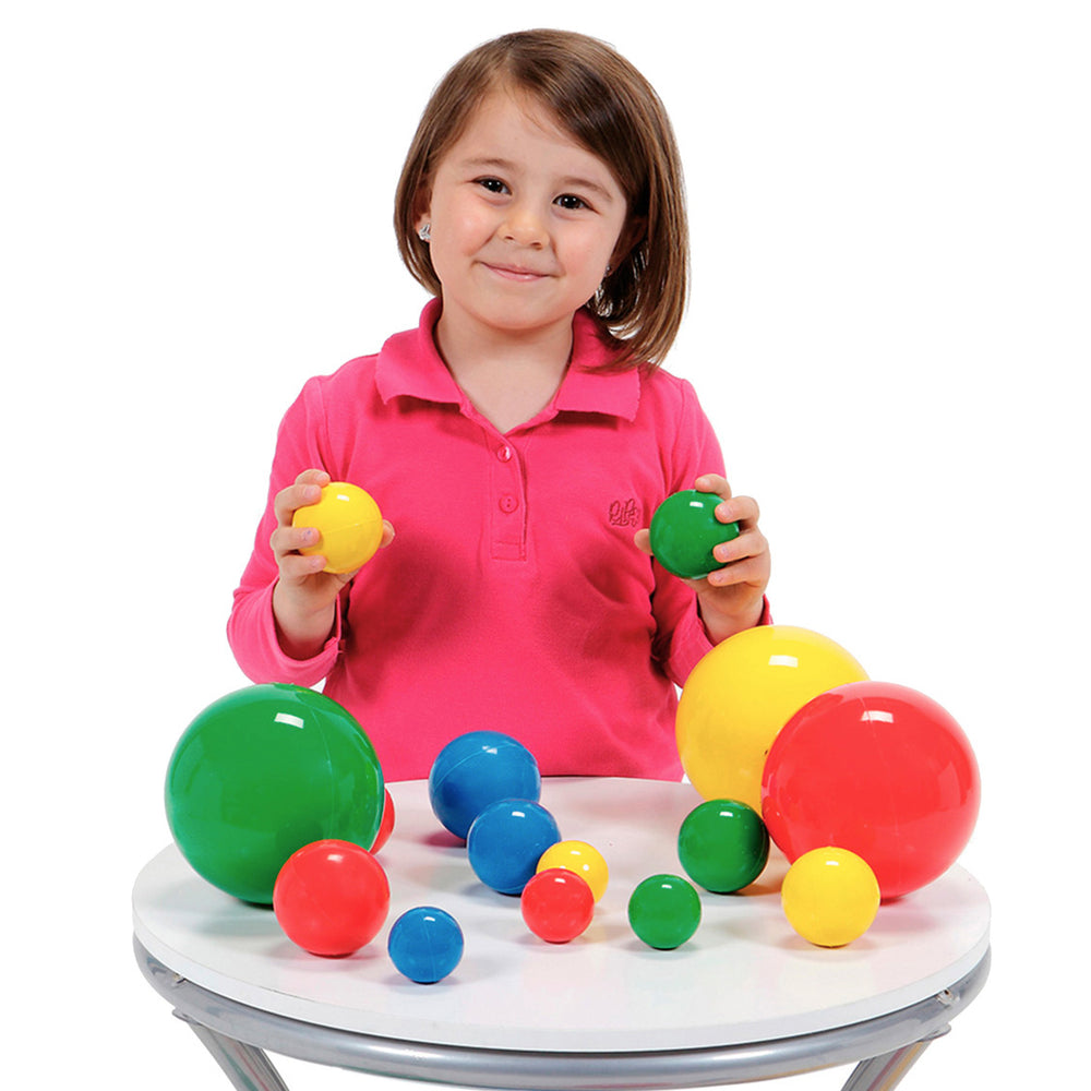 Girl playing with Gymnic 2-inch Set Of 24 Multicolored Balls in various sizes and colors on a white table.