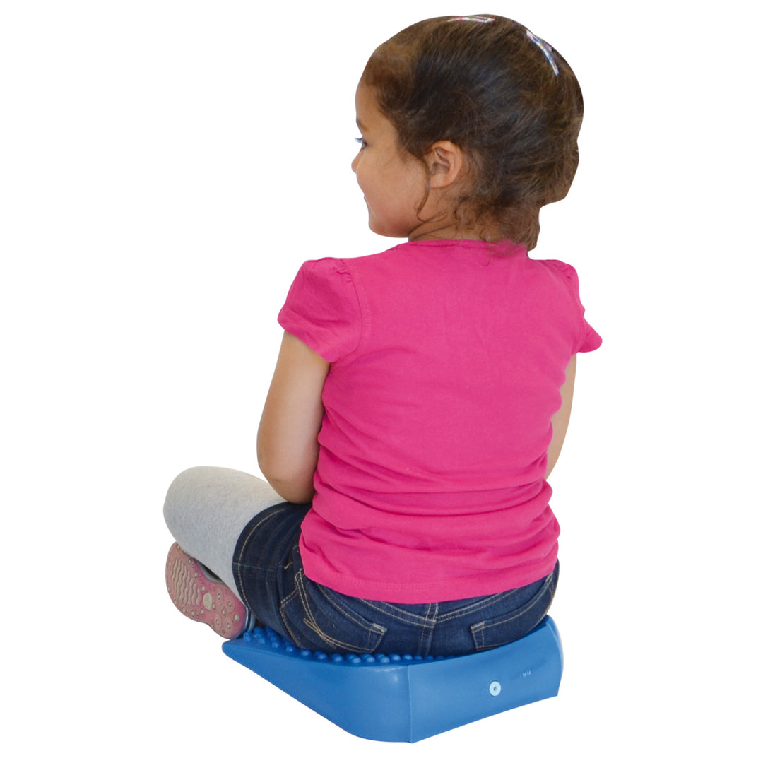 Child sitting on a blue Gymnic Movin' Sit Jr. inflatable wedge promoting correct posture and dynamic sitting.