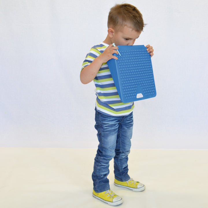 Child holding blue Gymnic Movin' Sit Jr. inflatable wedge designed for dynamic sitting and posture support.