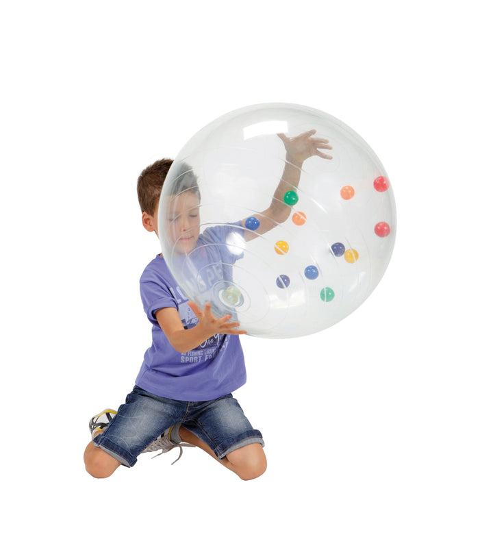 Child playing with transparent Gymnic Activity Ball containing colorful small balls inside for sensory and spatial skills.