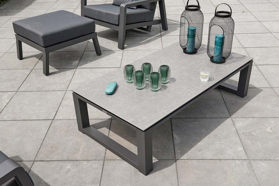 Primavera Coffee Table with aluminum frame and concrete look ceramic top on outdoor patio with decorative items.