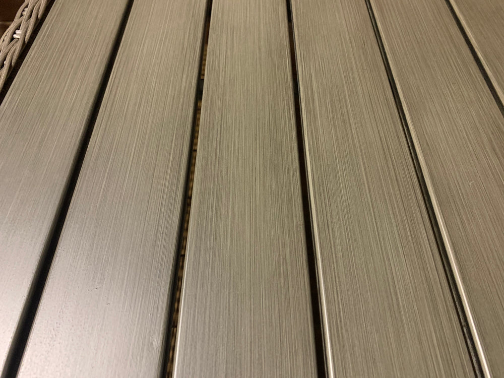 Palma Wicker Coffee Table close-up showing brushed aluminum faux wood top with dark oak poly resin slats and wicker frame detail.