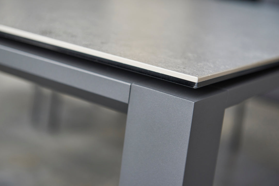 Primavera Coffee Table close-up showing ceramic top with concrete look and durable lava-colored aluminum frame.
