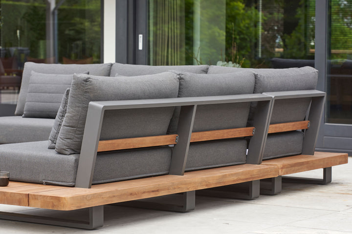 Fitz Roy Teak Corner Set with aluminum frame, Indonesian teak base, and weather-resistant gray cushions outdoors.