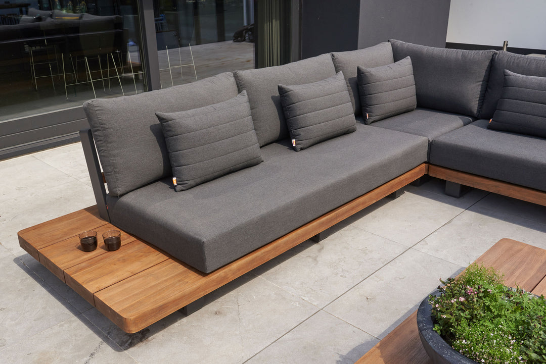 Fitz Roy Teak Corner Set with charcoal cushions and teak wood frame on a patio for outdoor seating and relaxation.