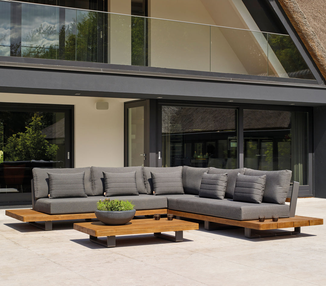 Fitz Roy Teak Corner Set outdoor lounge with gray cushions, teak wood base, and aluminum frame on patio
