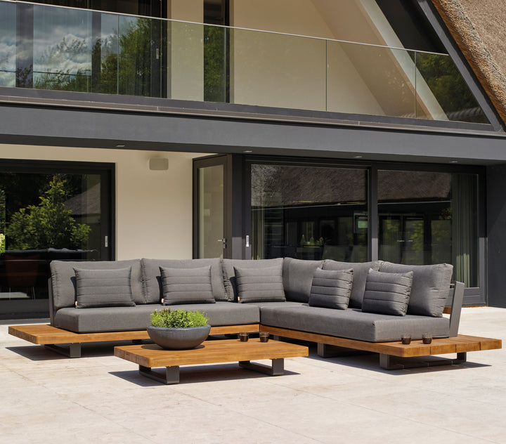 Fitz Roy Teak Corner Set outdoor lounge with gray cushions, teak wood base, and aluminum frame on patio