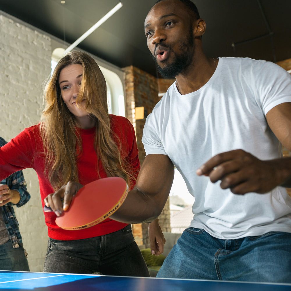 GTX-85 4-Player Set table tennis paddles used by two players enjoying a competitive game indoors.