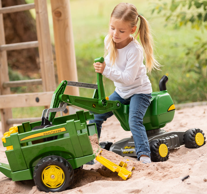 Young girl playing with John Deere Ride-On Digger in sandbox using real scooping and tipping action.