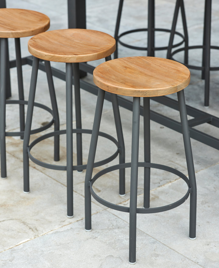 Canada Bar Height Dining Set with teak wood round seats and sturdy black metal frames on a tiled floor.