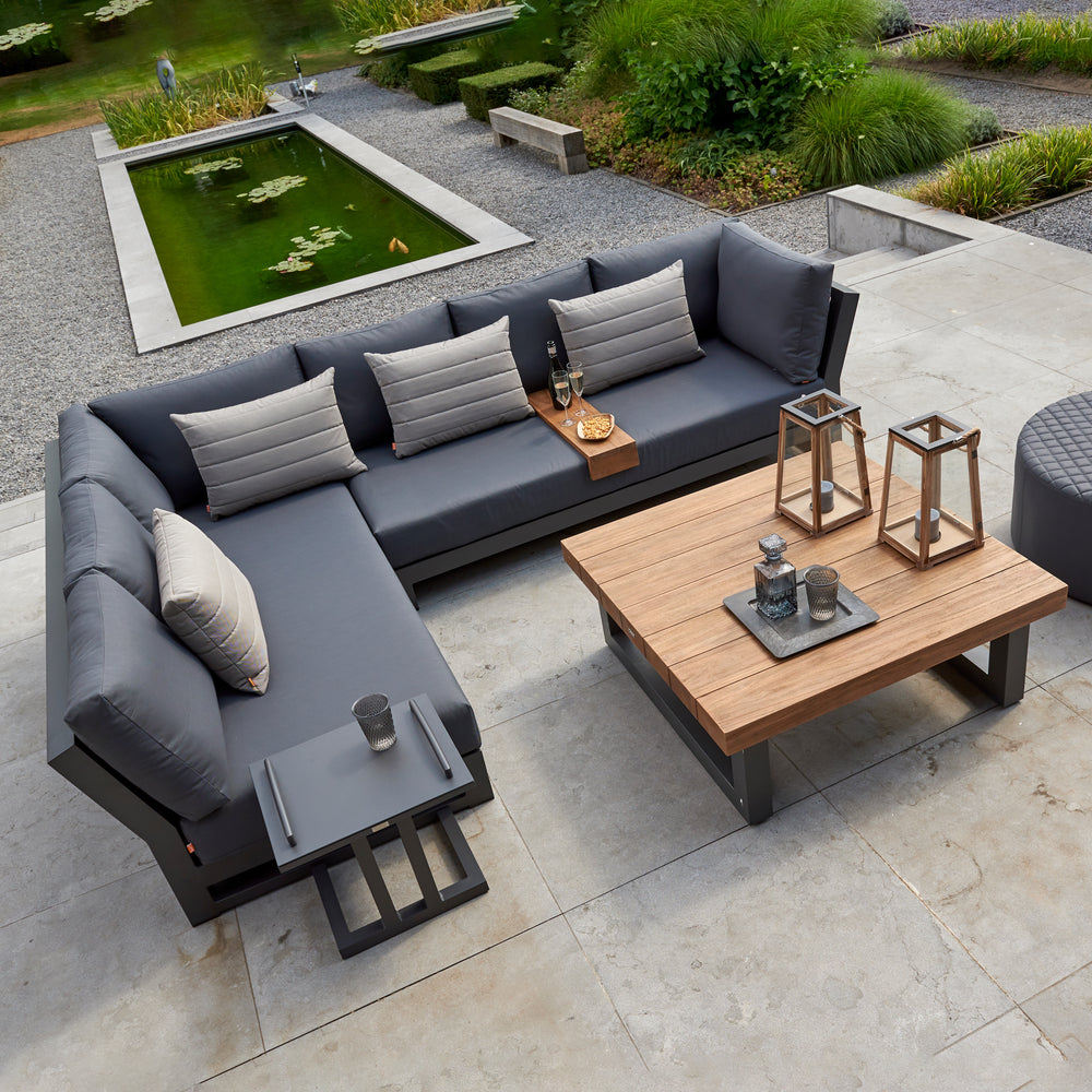Nevada Small Corner Conversation Set with lava aluminum frame, teak table, and Sunbrella cushions on outdoor patio.