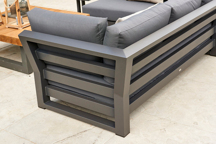 Close-up of the dark gray frame and cushions of the Nevada Right Sofa on an outdoor patio setting.