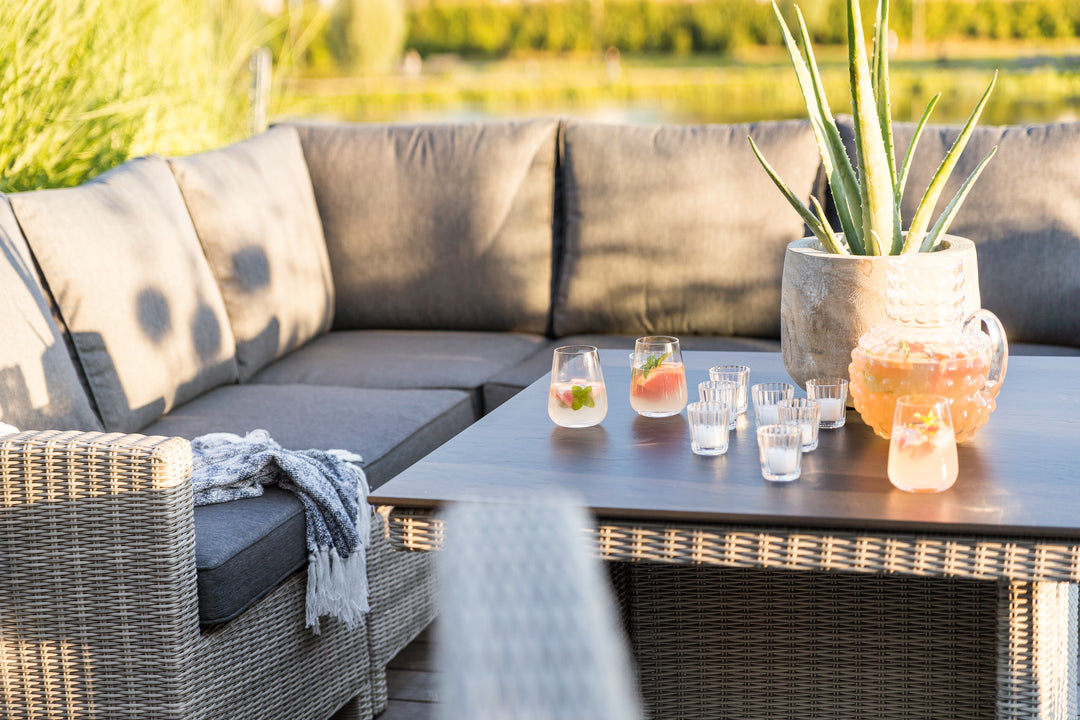 Palma Modular Wicker Right Arm Chair in outdoor setting with gray cushions and matching wicker dining table.
