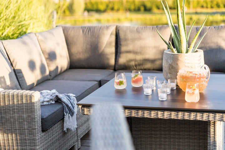 Palma Modular Wicker Right Arm Chair in outdoor setting with gray cushions and matching wicker dining table.