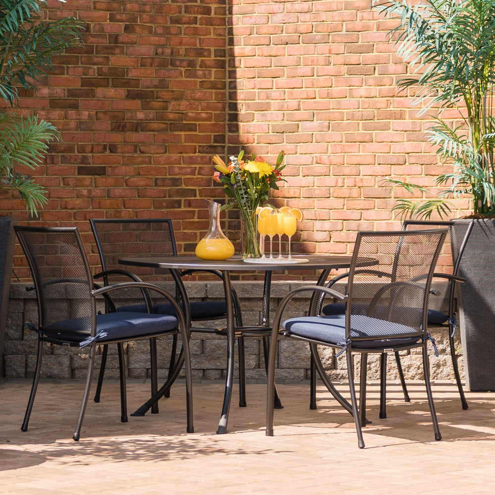 Pilano 5-Piece Wrought Iron Dining Set with 42-inch table and four mesh chairs in iron grey with seat cushions.