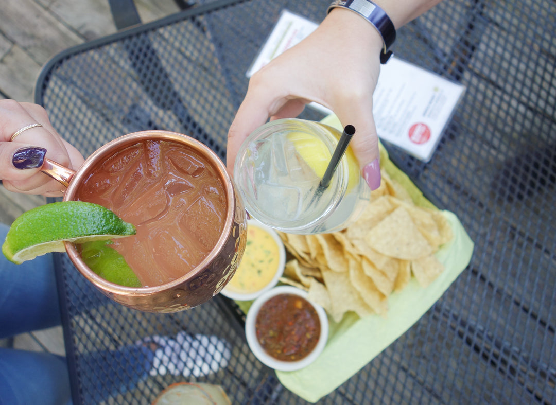 36-inch Square Mesh Bar Table in iron grey with mesh top holding drinks, chips, salsa, and queso dip on outdoor setting.