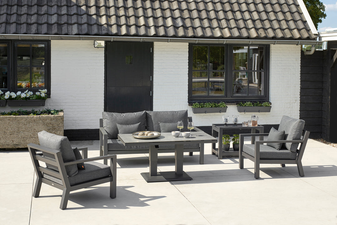 Timber Loveseat with charcoal cushions in outdoor patio setting with matching armchairs and adjustable table.