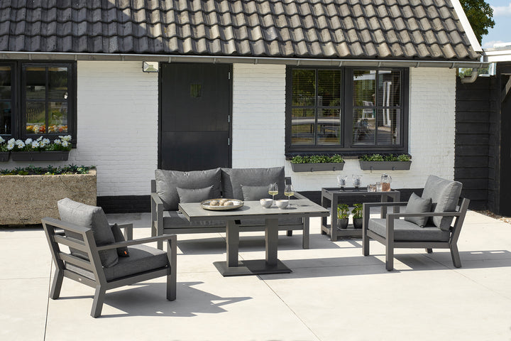 Timber Loveseat with charcoal cushions in outdoor patio setting with matching armchairs and adjustable table.