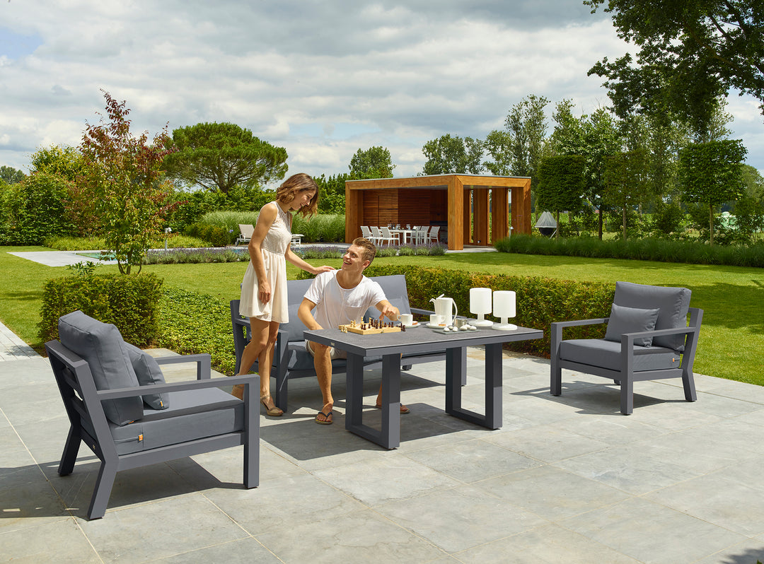 Timber Loveseat in lava frame with natte charcoal cushions shown in outdoor patio setting with ceramic table.