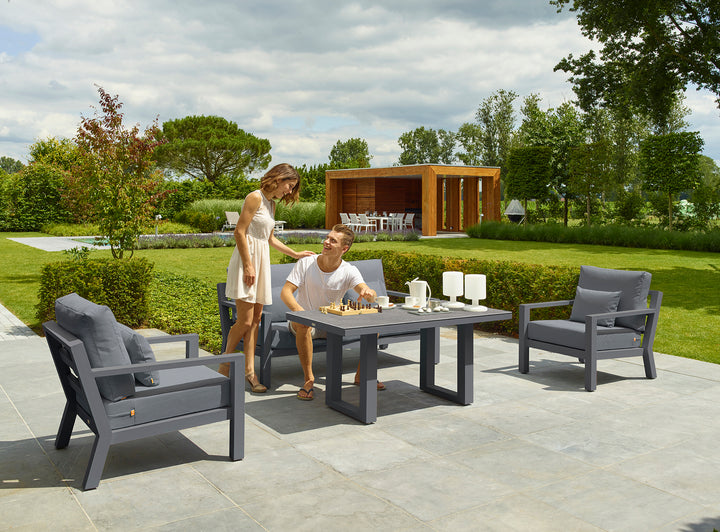 Timber Loveseat in lava frame with natte charcoal cushions shown in outdoor patio setting with ceramic table.
